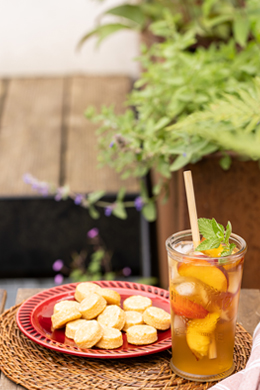 Verre d'infusion à la pêche glacée avec des Liabsti Abricot-passion sur une table de jardin ensoleillée.