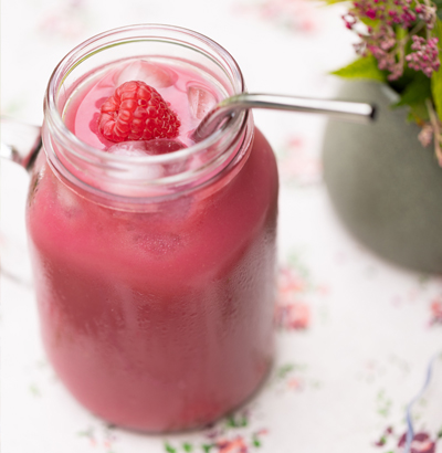 Un grand verre transparent d'un attrayant smoothie aux framboises d'un rose éclatant.