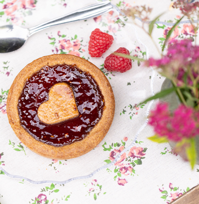 Une superbe Tartelette Linzer à la framboise, décorée de framboises.