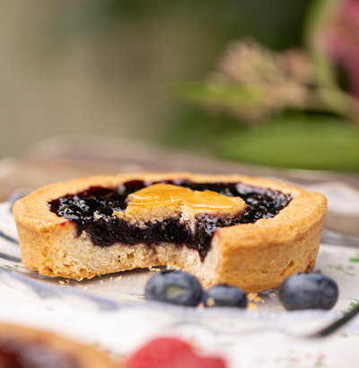 Une appétissante Tartelette Linzer aux myrtilles sauvages des Vosges, tranchée et décorée de myrtilles.