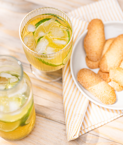 A glass and carafe of jasmin iced tea with lime, of sparkling colors, with a plate of crunchy Croquiets.